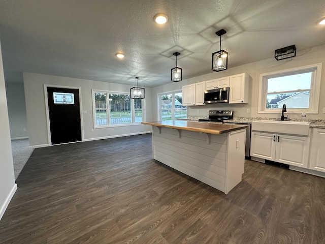 kitchen with appliances with stainless steel finishes, dark wood-style flooring, a sink, and a textured ceiling