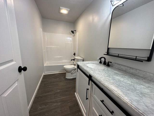 full bathroom with baseboards, toilet, vanity, wood finished floors, and shower / bathtub combination