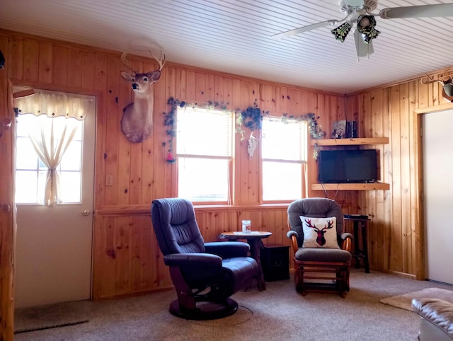 living area with a wealth of natural light, wood walls, and carpet