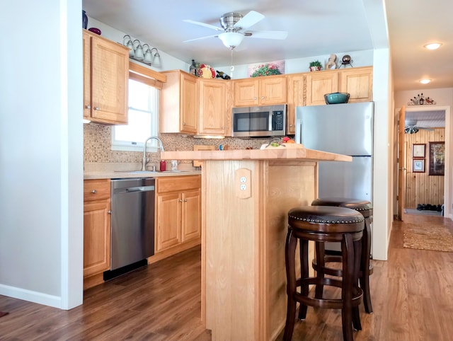 kitchen featuring stainless steel appliances, light countertops, decorative backsplash, light brown cabinets, and a sink