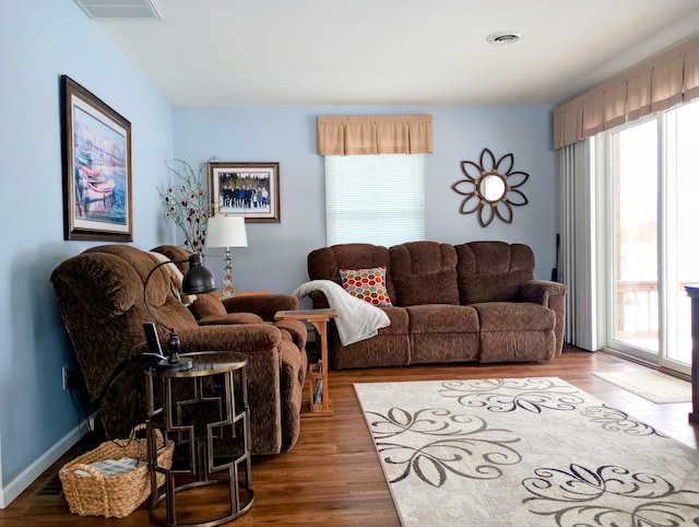 living room with dark wood-style floors, visible vents, and baseboards