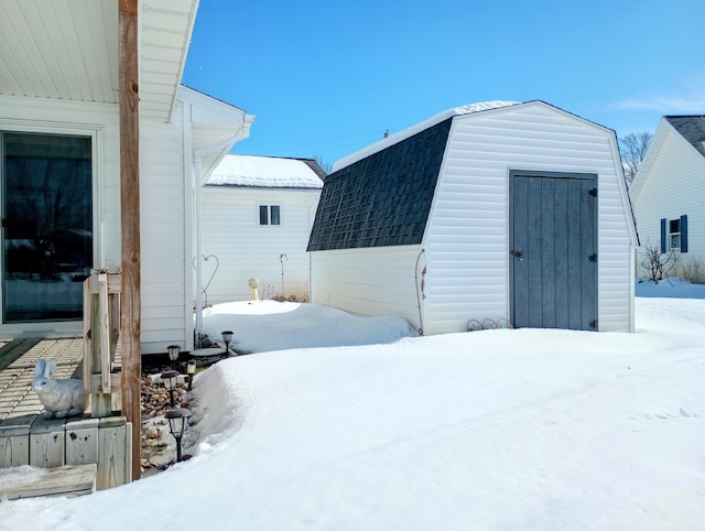 yard layered in snow featuring a storage shed and an outbuilding