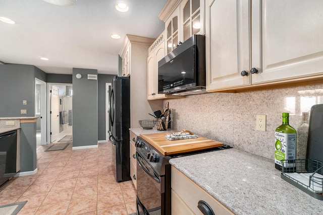 kitchen featuring glass insert cabinets, tasteful backsplash, black appliances, and light tile patterned floors