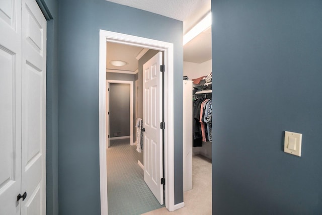 hall with a textured ceiling and light colored carpet