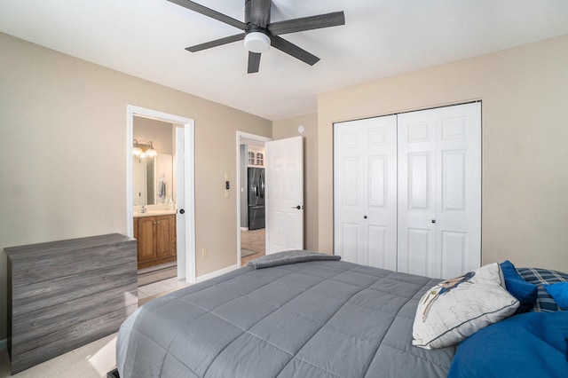 bedroom featuring baseboards, ensuite bath, ceiling fan, black fridge, and a closet