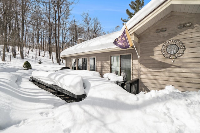 view of snow covered exterior with a chimney