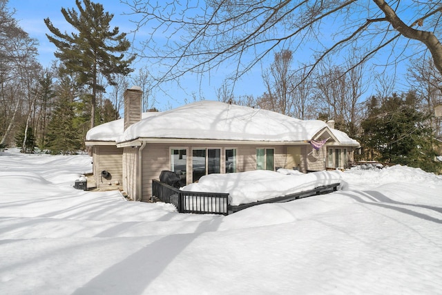 snow covered rear of property with a chimney