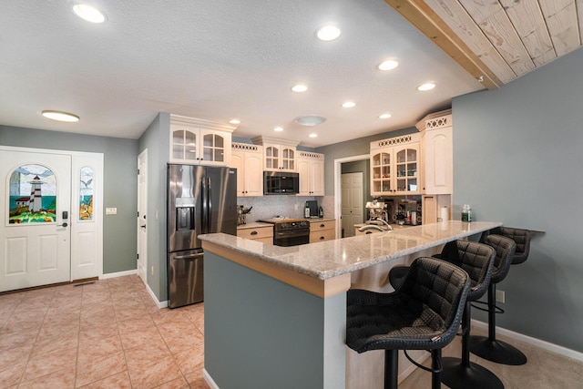 kitchen featuring backsplash, refrigerator with ice dispenser, range, a peninsula, and a kitchen breakfast bar