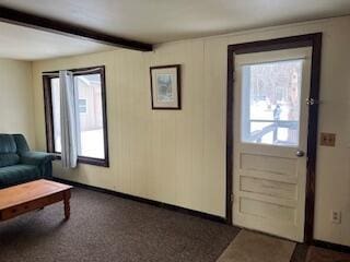 doorway with baseboards, dark colored carpet, a wealth of natural light, and beamed ceiling