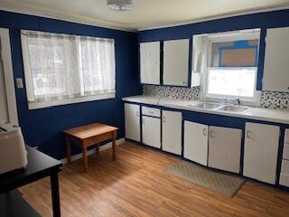 kitchen with tasteful backsplash, white cabinets, light countertops, and light wood finished floors