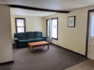 carpeted living room with beam ceiling and baseboards