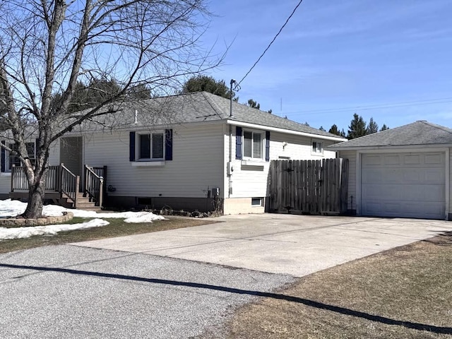 view of property exterior with fence, concrete driveway, roof with shingles, a garage, and an outbuilding