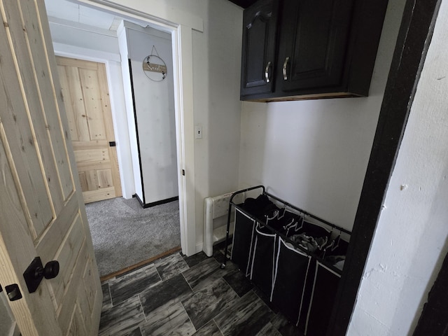 hallway featuring dark carpet and stone finish flooring