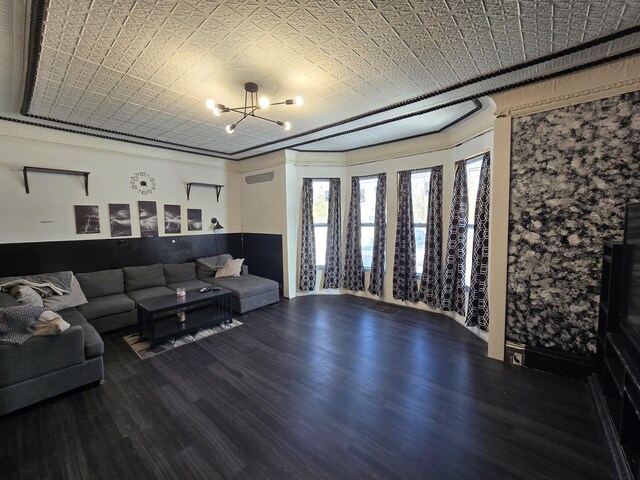 living room with a chandelier, an ornate ceiling, and wood finished floors