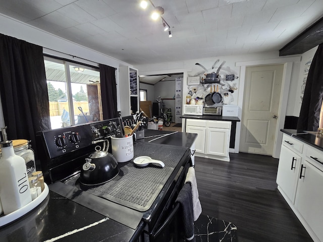 kitchen with dark wood-style floors, white microwave, black electric range, white cabinetry, and dark countertops