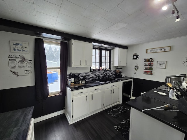 kitchen featuring a sink, dark countertops, dark wood-style floors, white cabinets, and baseboards