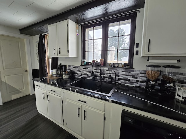 kitchen with dishwasher, dark countertops, white cabinets, and a sink