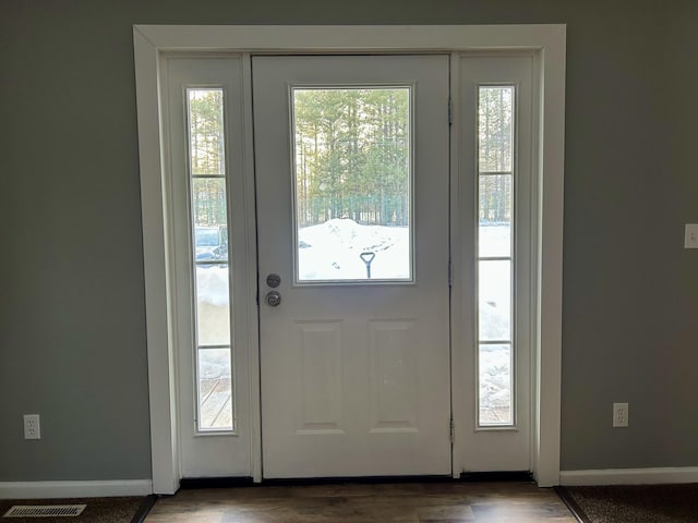 doorway featuring baseboards, visible vents, and wood finished floors