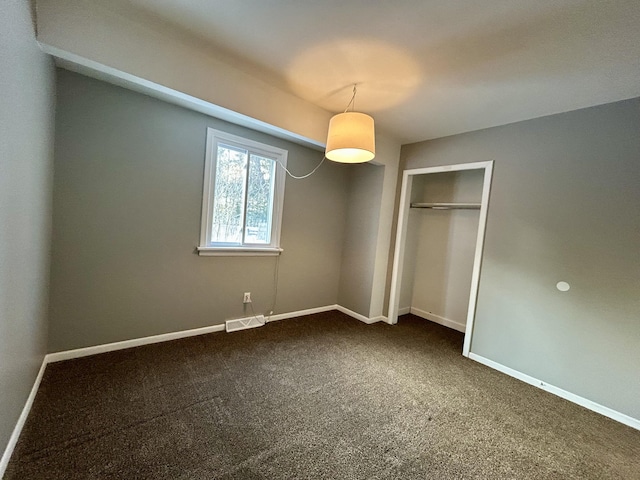 unfurnished bedroom featuring visible vents, dark carpet, and baseboards