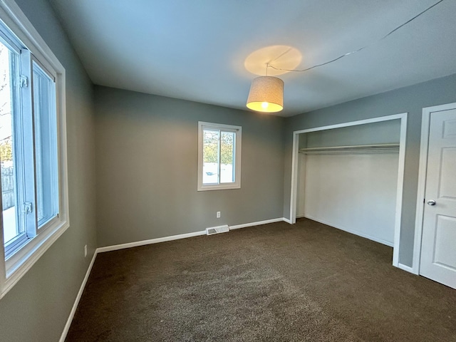 unfurnished bedroom featuring baseboards, visible vents, and dark carpet