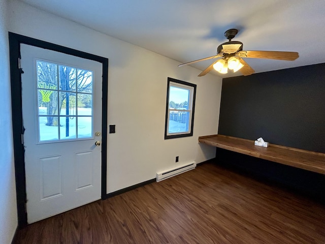 doorway featuring a baseboard heating unit, dark wood-type flooring, ceiling fan, and baseboards