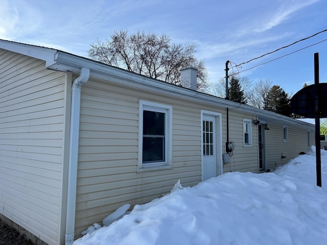 view of snow covered exterior with a chimney