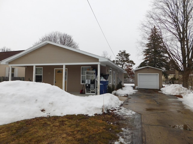 view of front of house with driveway, covered porch, a detached garage, and an outbuilding