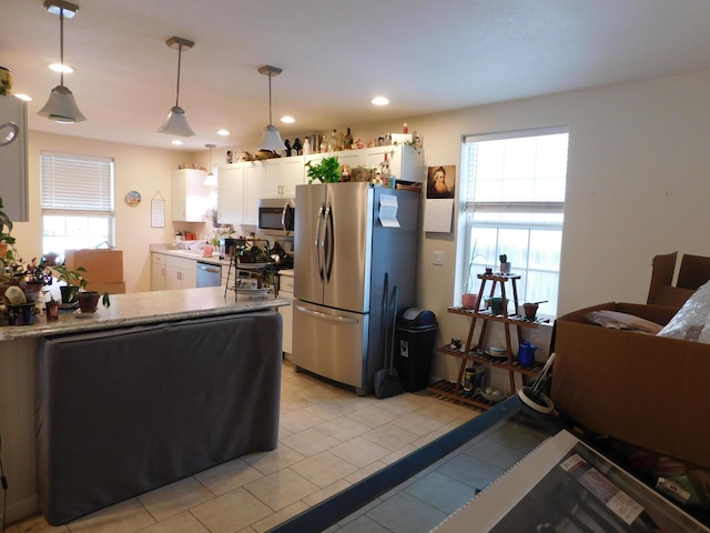 kitchen featuring hanging light fixtures, white cabinetry, appliances with stainless steel finishes, and a wealth of natural light