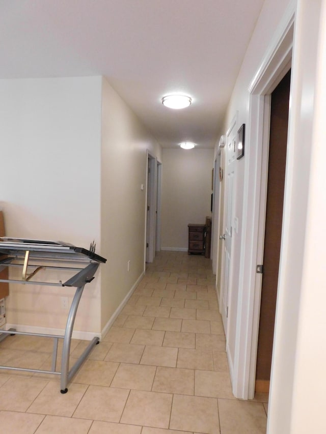 corridor featuring light tile patterned floors and baseboards