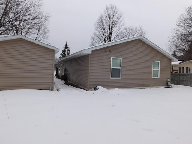 snow covered rear of property featuring fence