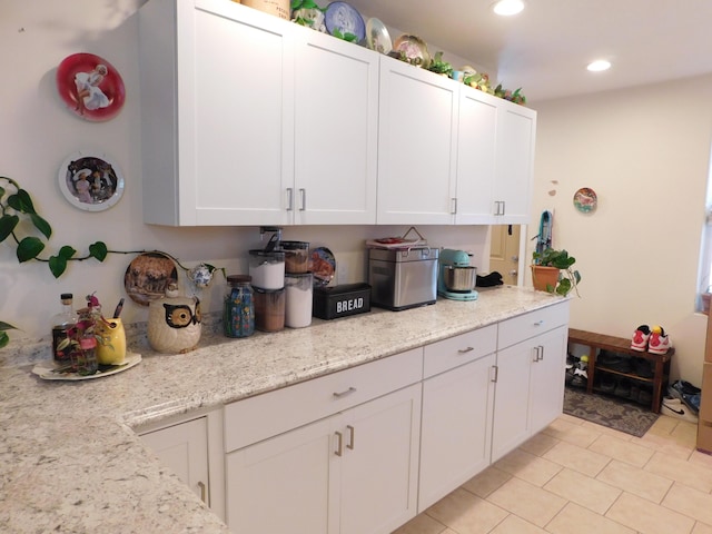 kitchen with light tile patterned floors, light stone countertops, white cabinetry, and recessed lighting