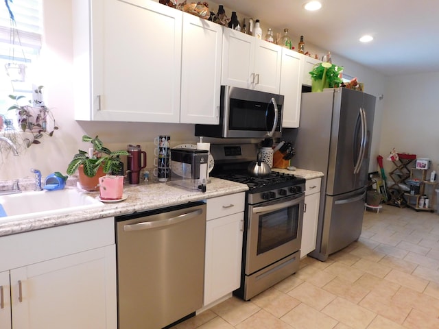 kitchen with light stone counters, recessed lighting, a sink, white cabinets, and appliances with stainless steel finishes