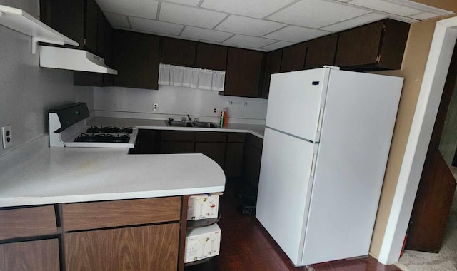 kitchen featuring under cabinet range hood, light countertops, freestanding refrigerator, and range with gas stovetop