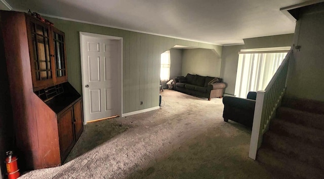 living room with arched walkways, carpet floors, ornamental molding, and baseboards