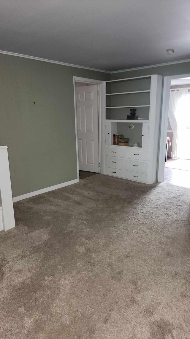 unfurnished living room featuring ornamental molding, carpet flooring, and baseboards