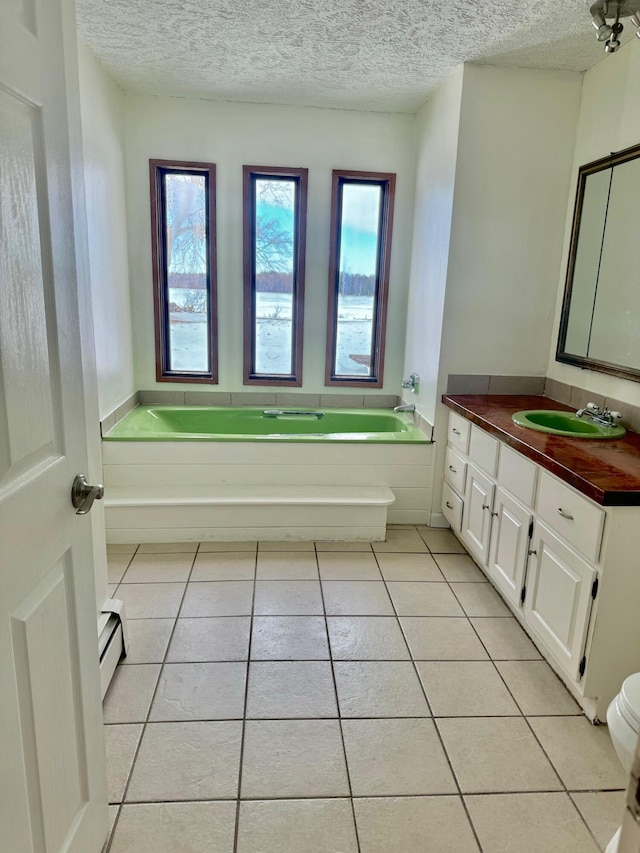 bathroom featuring a garden tub, tile patterned flooring, baseboard heating, a textured ceiling, and vanity