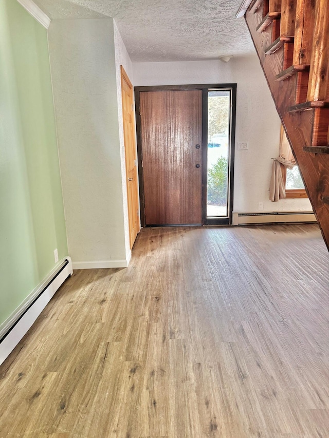 interior space with baseboards, a textured ceiling, a baseboard heating unit, and wood finished floors