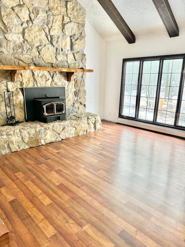 unfurnished living room with a textured ceiling, a baseboard radiator, wood finished floors, and plenty of natural light