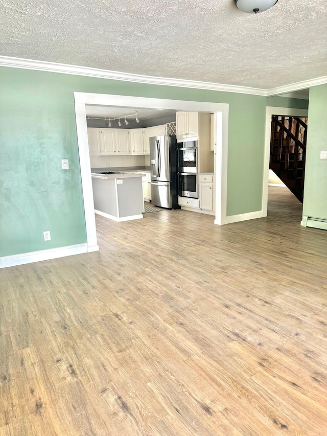 unfurnished living room featuring ornamental molding, a baseboard heating unit, a textured ceiling, light wood-type flooring, and baseboards