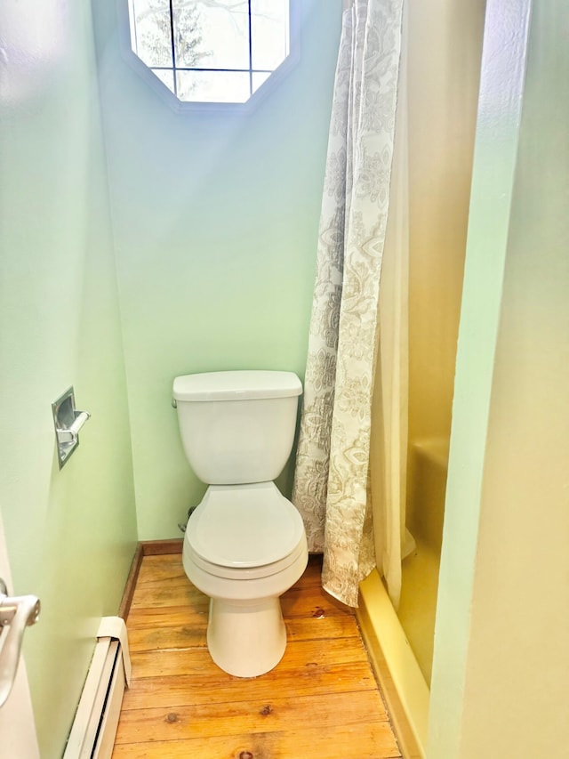 full bath with baseboards, toilet, wood finished floors, curtained shower, and a baseboard heating unit