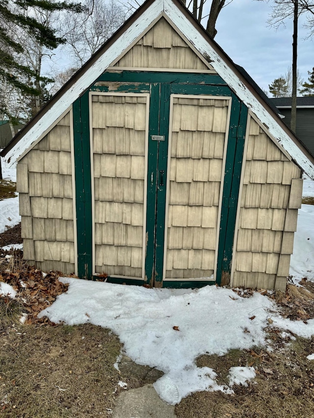 snow covered structure with an outdoor structure and a storage shed