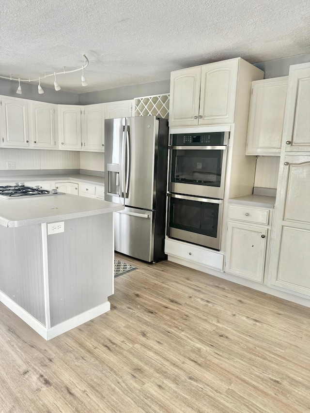 kitchen with white cabinets, light wood-style floors, appliances with stainless steel finishes, and light countertops