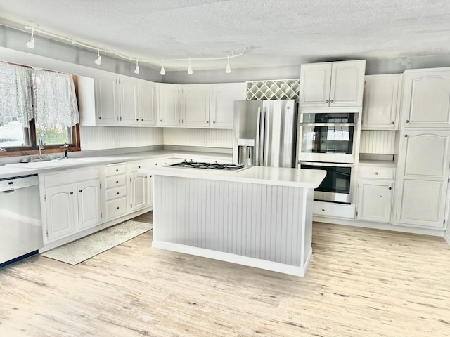 kitchen featuring light wood-type flooring, white cabinetry, appliances with stainless steel finishes, and a sink