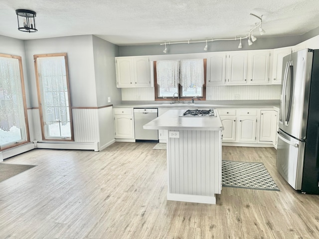 kitchen featuring stainless steel appliances, light countertops, light wood-style flooring, white cabinets, and a sink