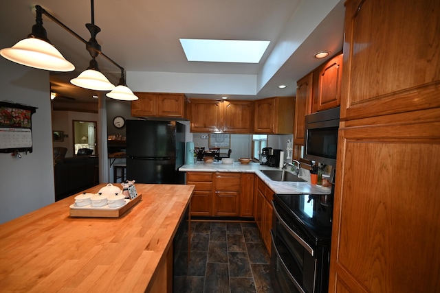 kitchen with butcher block counters, a skylight, freestanding refrigerator, double oven range, and stainless steel microwave