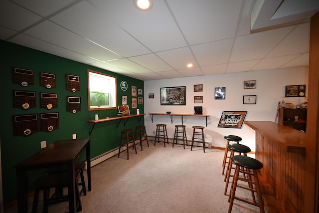 bar with carpet, a drop ceiling, a bar, and a baseboard radiator