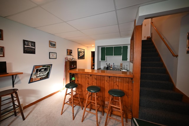 bar featuring carpet floors, a dry bar, a paneled ceiling, stairway, and baseboards