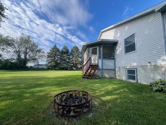 view of yard with entry steps, a sunroom, and a fire pit