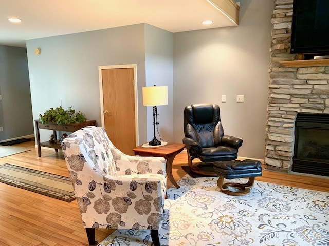 living area featuring a stone fireplace, recessed lighting, and light wood-style floors