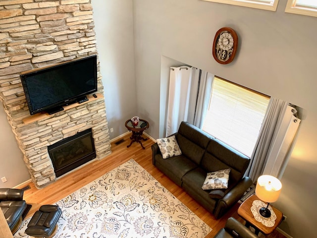 living area featuring a fireplace, wood finished floors, visible vents, and baseboards